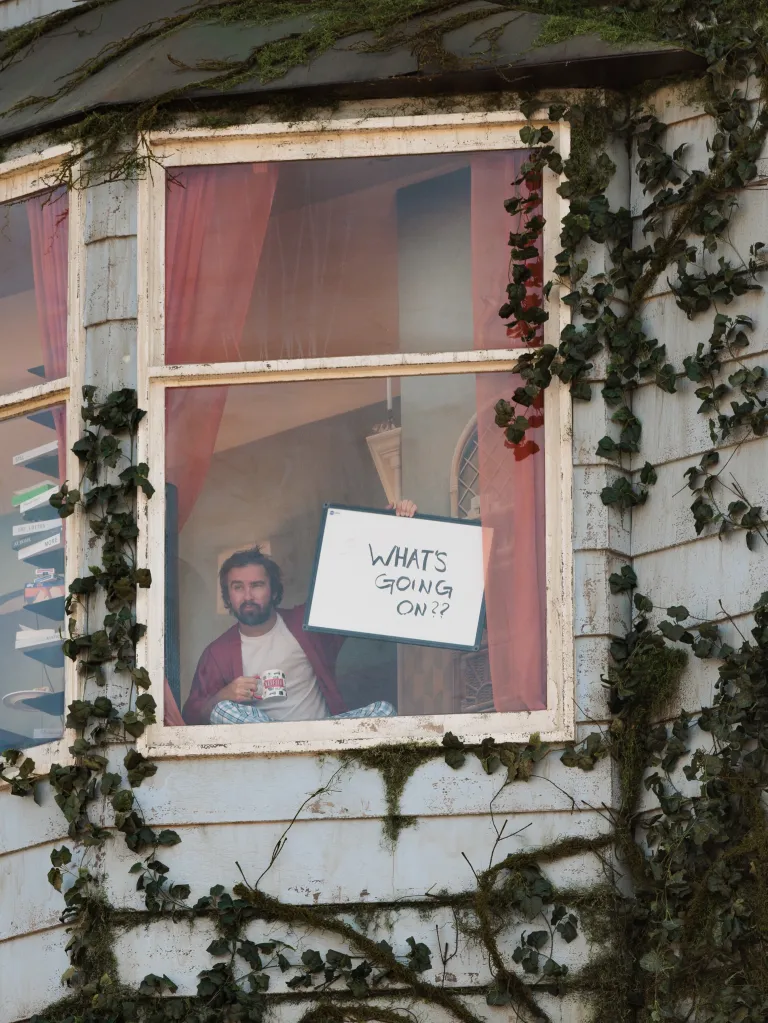 A man holds a whiteboard that reads 