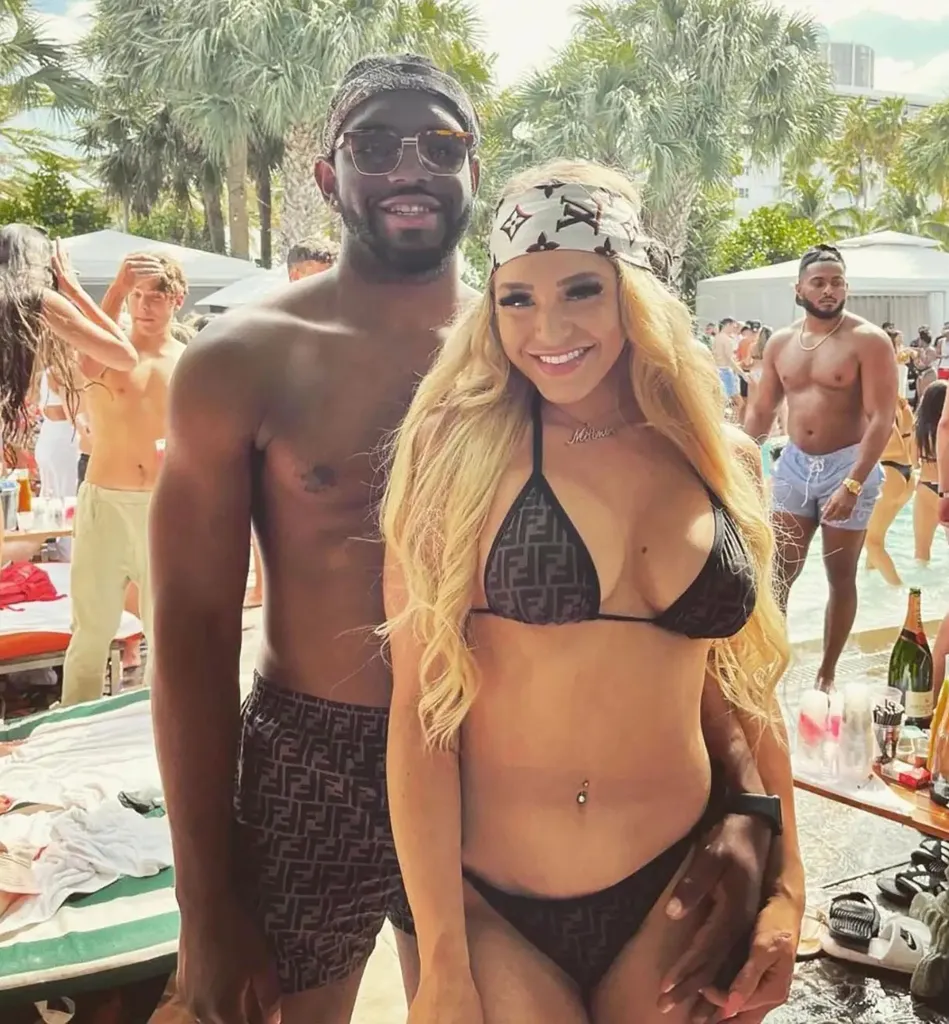 Courtney Clenney and Christian Obumseli smiling at the camera at a pool party.