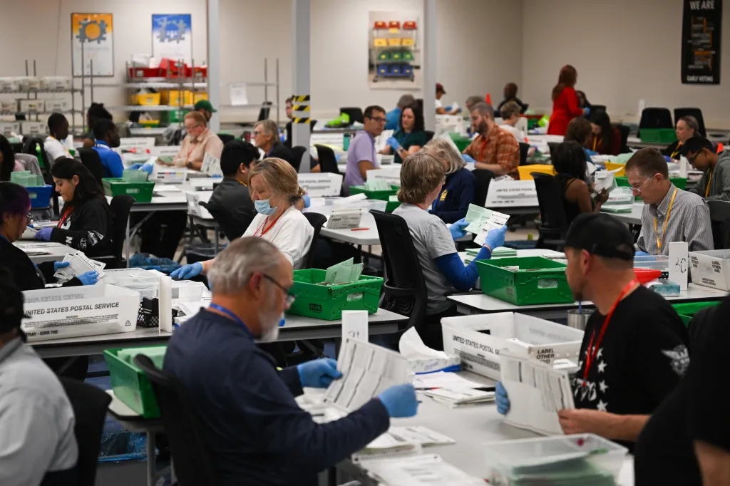 Pairs of election workers from different political parties open and inspect mail-in ballot envelopes containing voted ballots after they completed signature verification during processing inside the Maricopa County Tabulation and Election Center (MCTEC) on Nov. 5, 2024, in Phoenix, Arizona. 