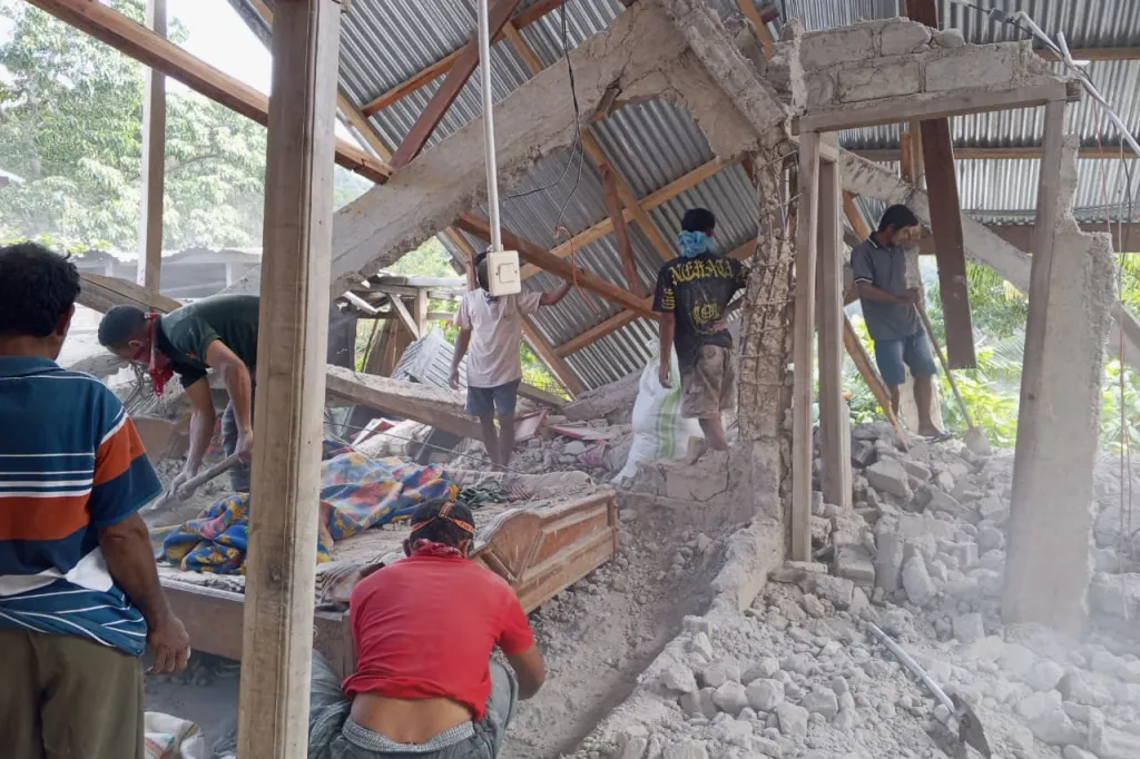 People begin to clean the rubble of a home destroyed in the earthquake.