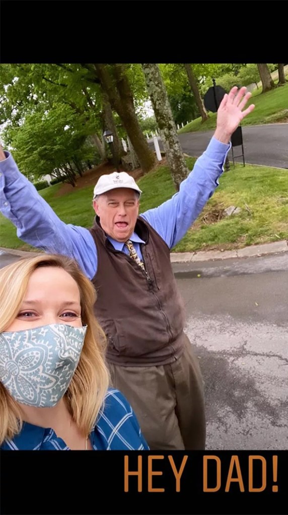 Reese Witherspoon taking a selfie with her father John, who stands behind her with his arms raised.