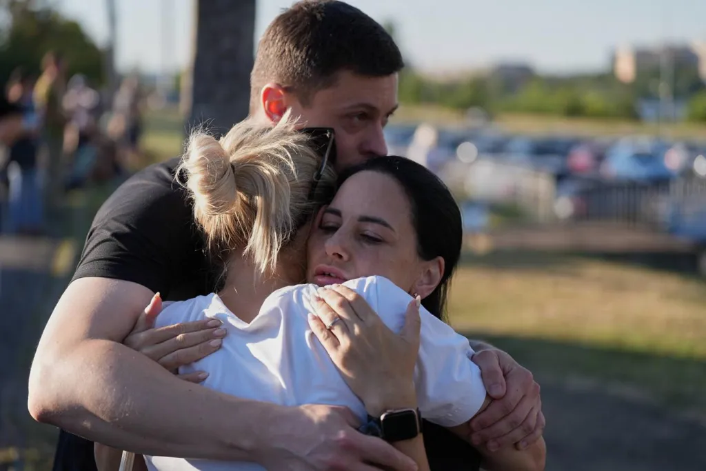People embrace near a burning shopping mall in Kryvyi Rih, Ukraine, following a Russian drone attack.