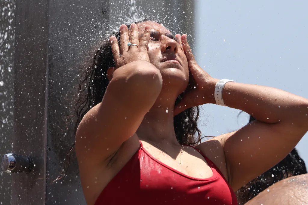 A person in a red swimsuit showers at Venice Beach.