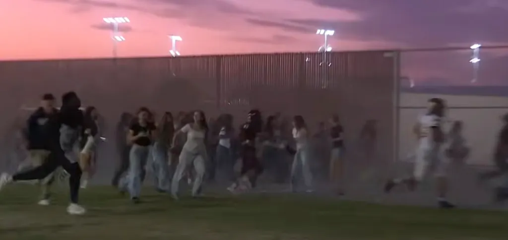 People and football players run for safety after a shooting at Independence High School in Bakersfield, California.