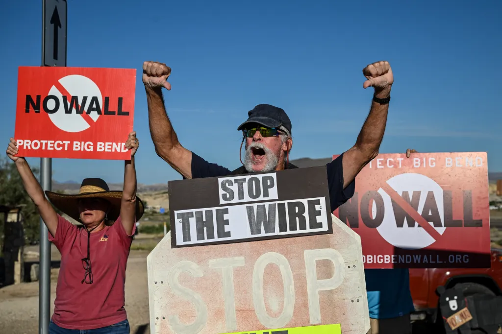 Protesters hold signs that read 