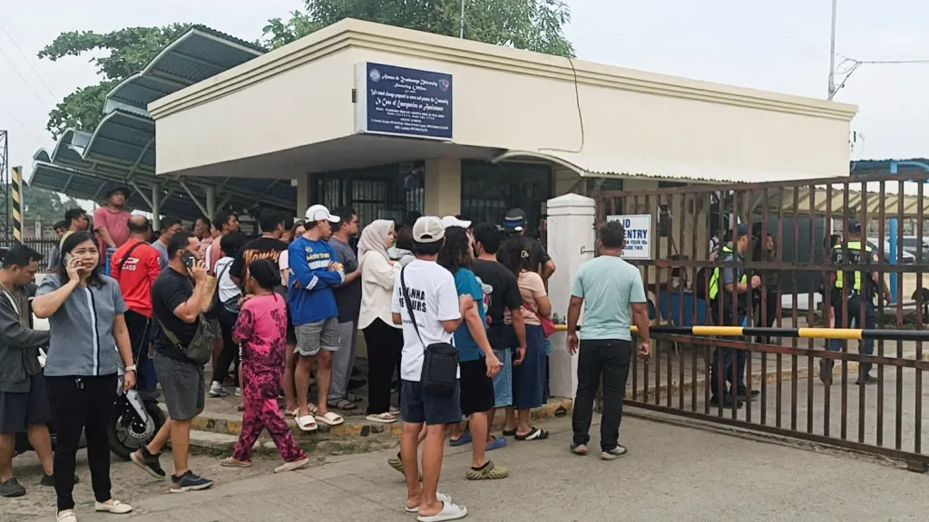 People stand outside Ateneo de Zamboanga University after a shooting that killed two people in Zamboanga, southern Philippines, on Tuesday, Aug. 18, 2026.