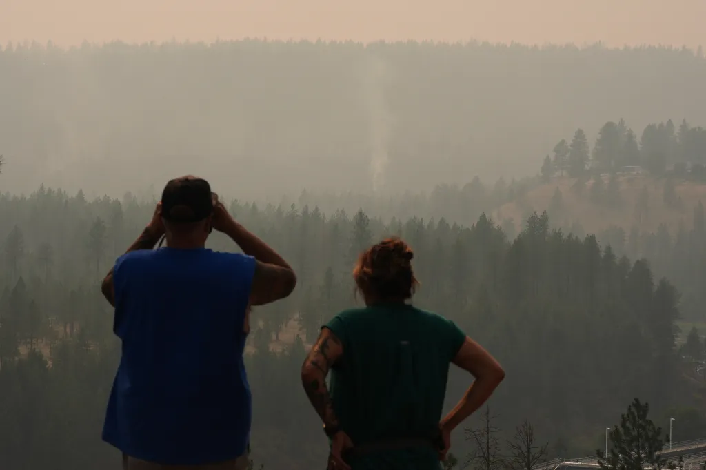 People view smoke rising from the Old Trails wildfire in the northwest part of Spokane, Wash., Monday, Aug. 3, 2026.