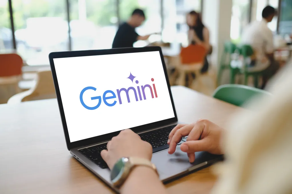 A person using a laptop with the Google Gemini AI logo displayed on the screen.