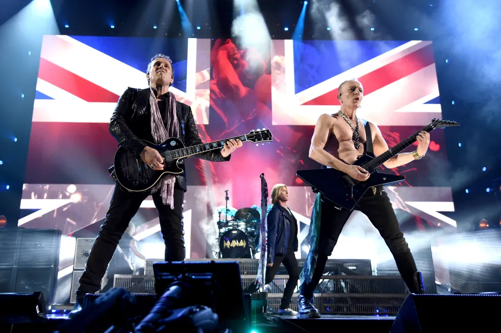 Def Leppard members Vivian Campbell, Joe Elliott, and Phil Collen performing on stage during the Rock & Roll Hall of Fame Induction Ceremony.