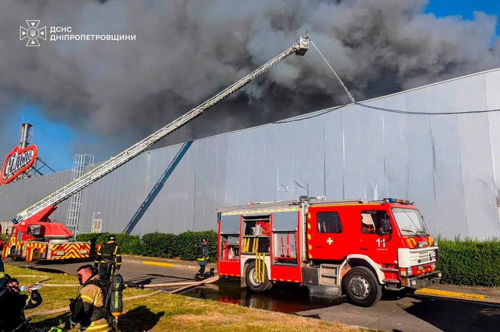 Firefighters spraying water on a burning shopping mall in Kryvyi Rih after a Russian strike.