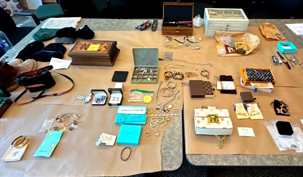 A table covered with brown paper, laden with various pieces of jewelry, watches, boxes, small bags, and hats.