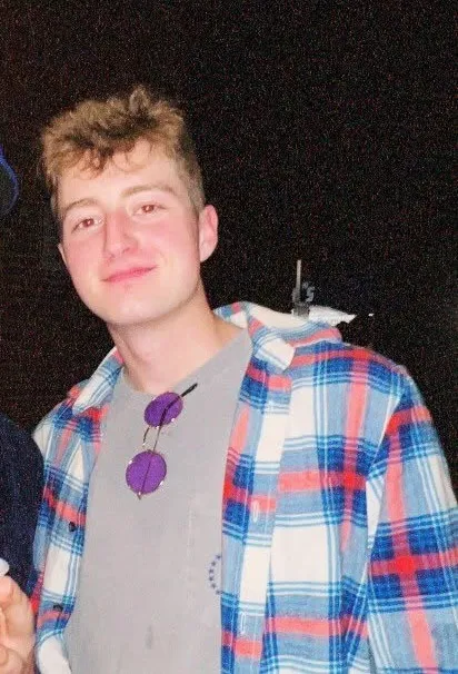 Thomas Robinson wearing a gray t-shirt and blue, red, and white plaid shirt.