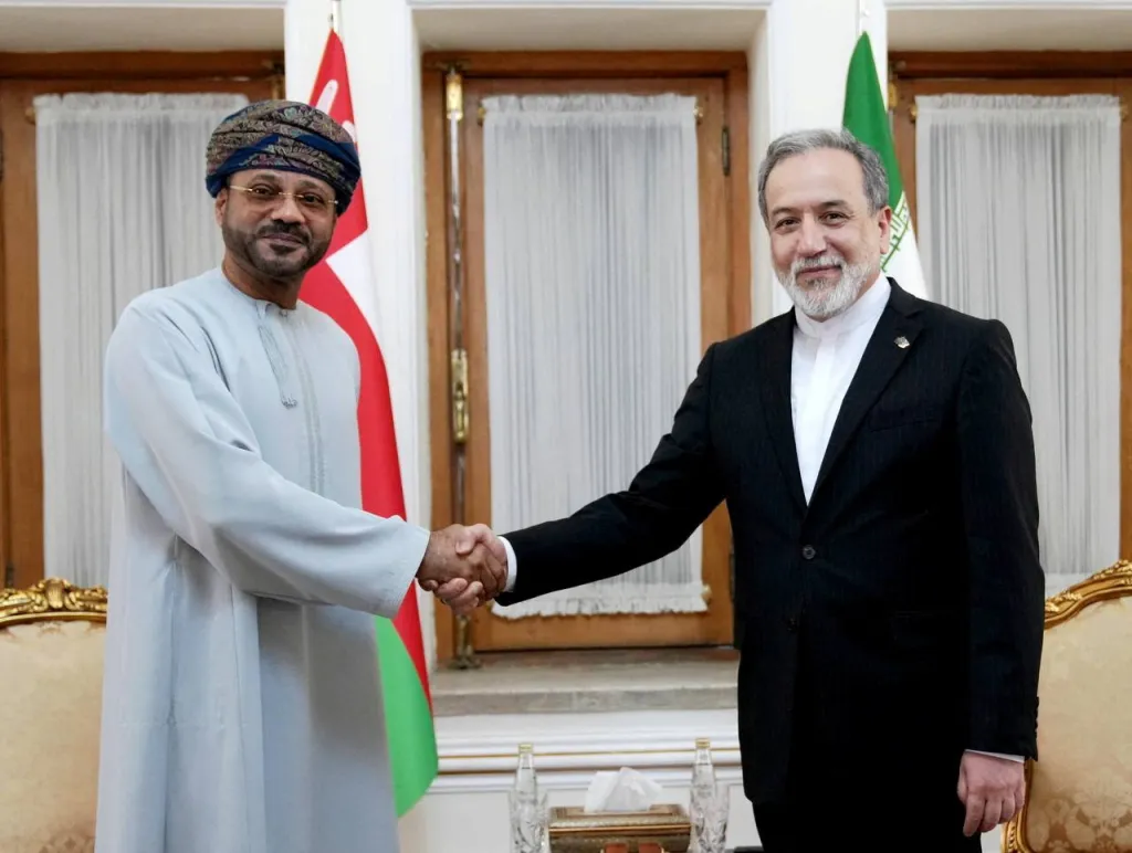 Oman's Foreign Minister Sayyid Badr al-Busaidi shakes hands with Iran's Foreign Minister Abbas Araghchi in Tehran.
