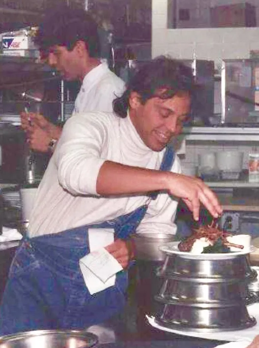 Anthony Bourdain and John Tesar working in a kitchen.