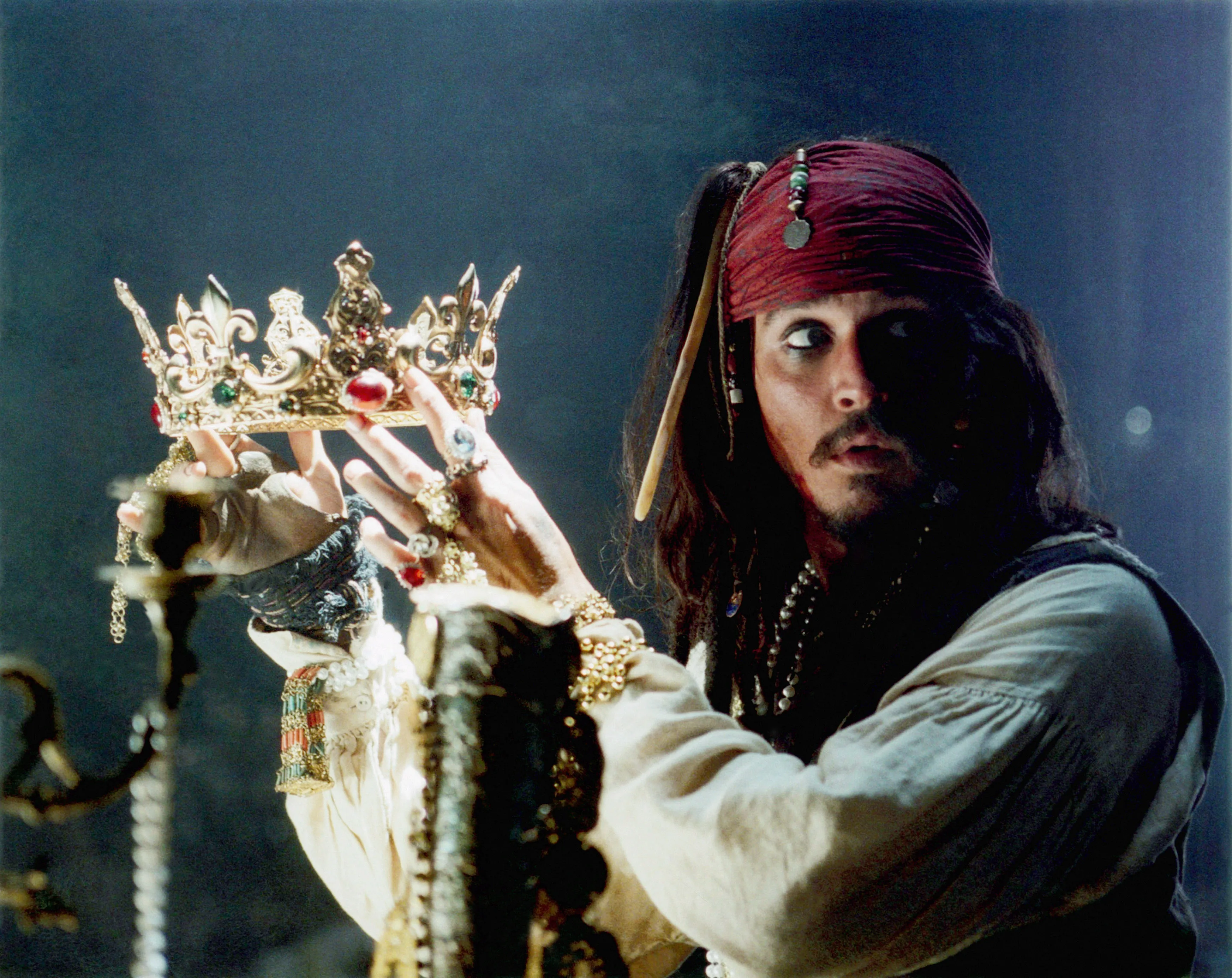Johnny Depp as Jack Sparrow holding a golden crown in Pirates of the Caribbean.