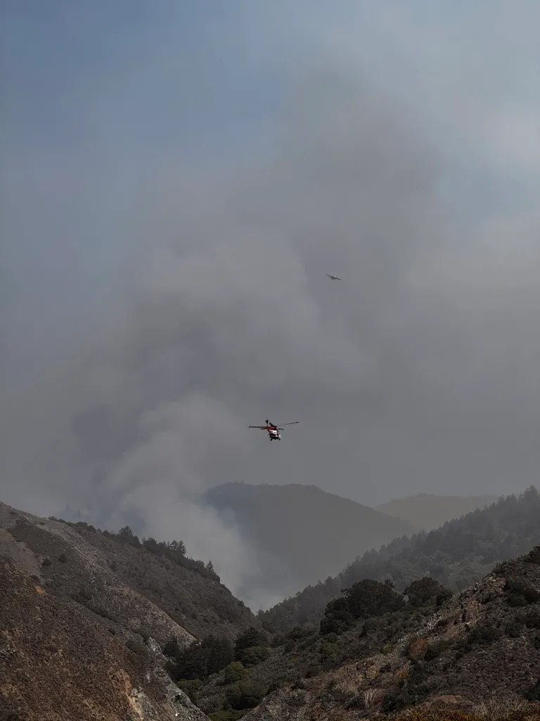 Helicopter and airplane flying above a canyon filled with smoke from the Plaskett Fire in Big Sur.