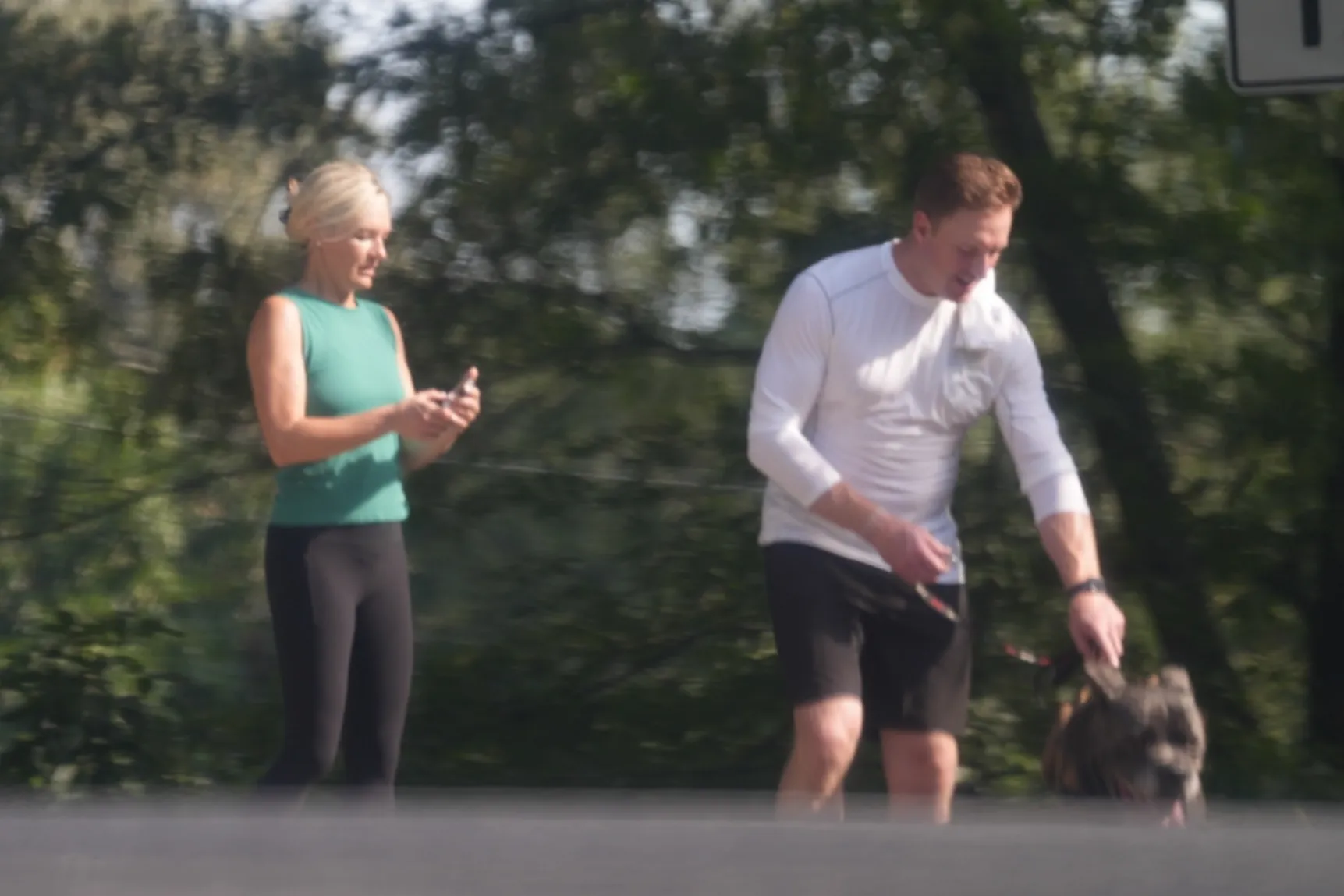 Kroy Biermann walking a dog and Jillian Green looking at her phone during a hike.