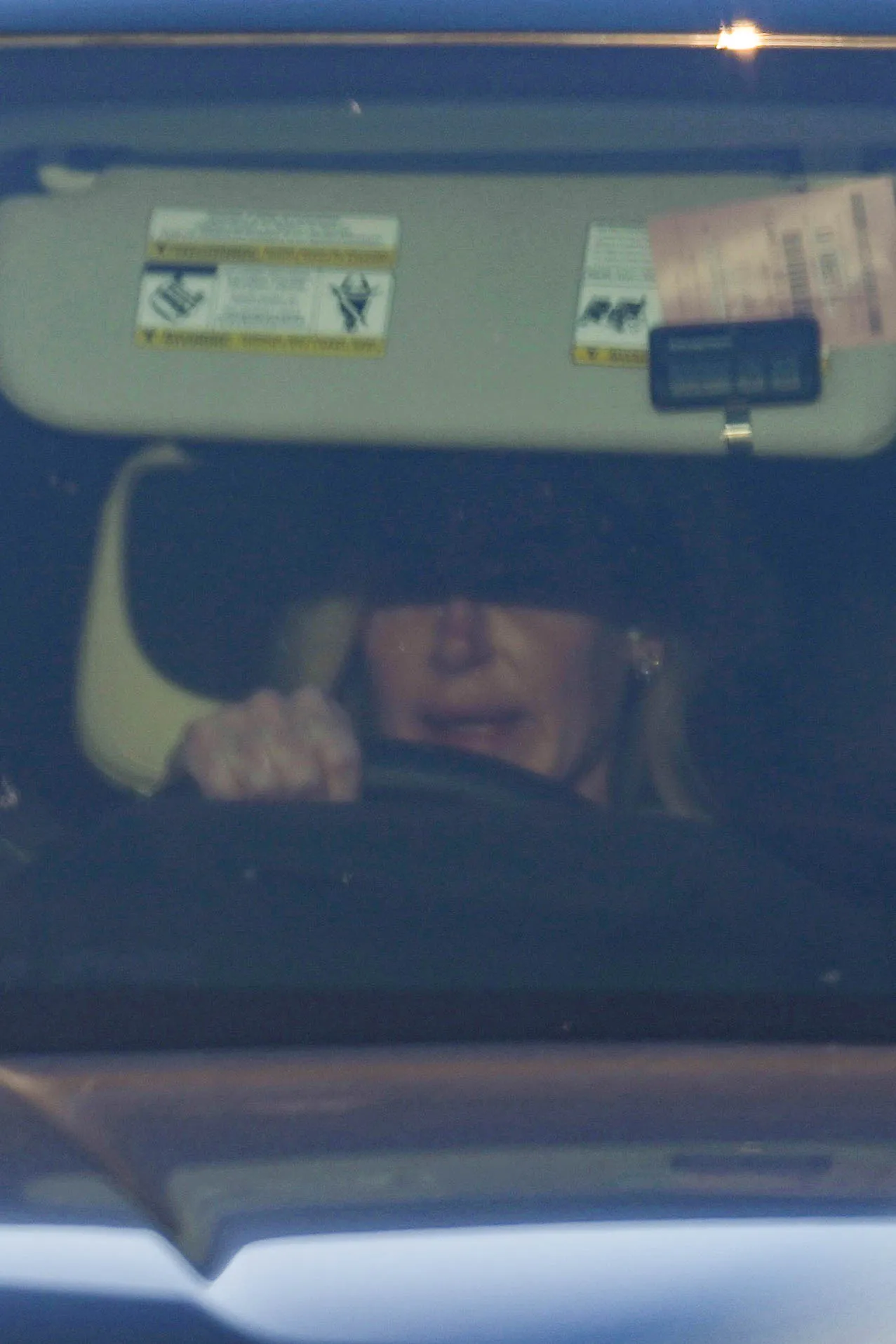 Kim Zolciak driving a car, seen through the windshield.