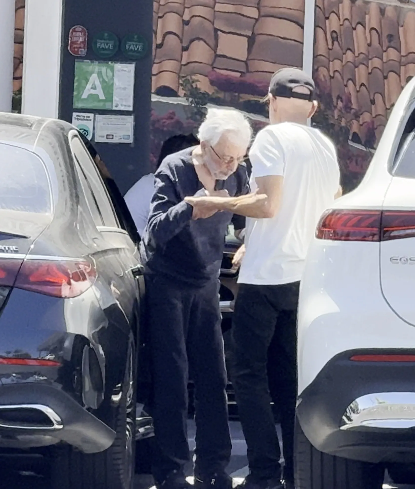 Frankie Valli being assisted by a caretaker while leaving a car.