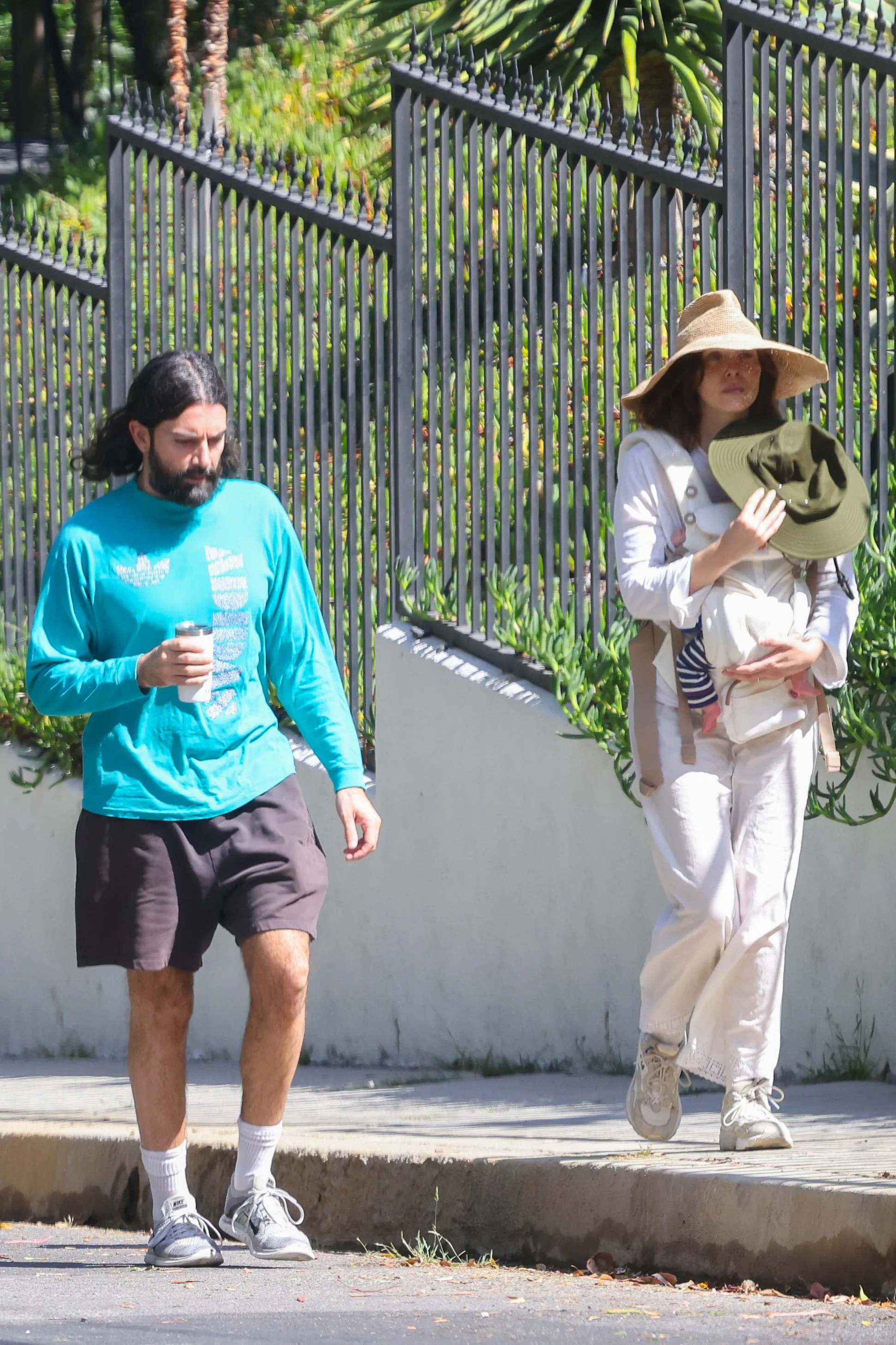 Elizabeth Olsen with a baby in a carrier and Robbie Arnett walking beside her.