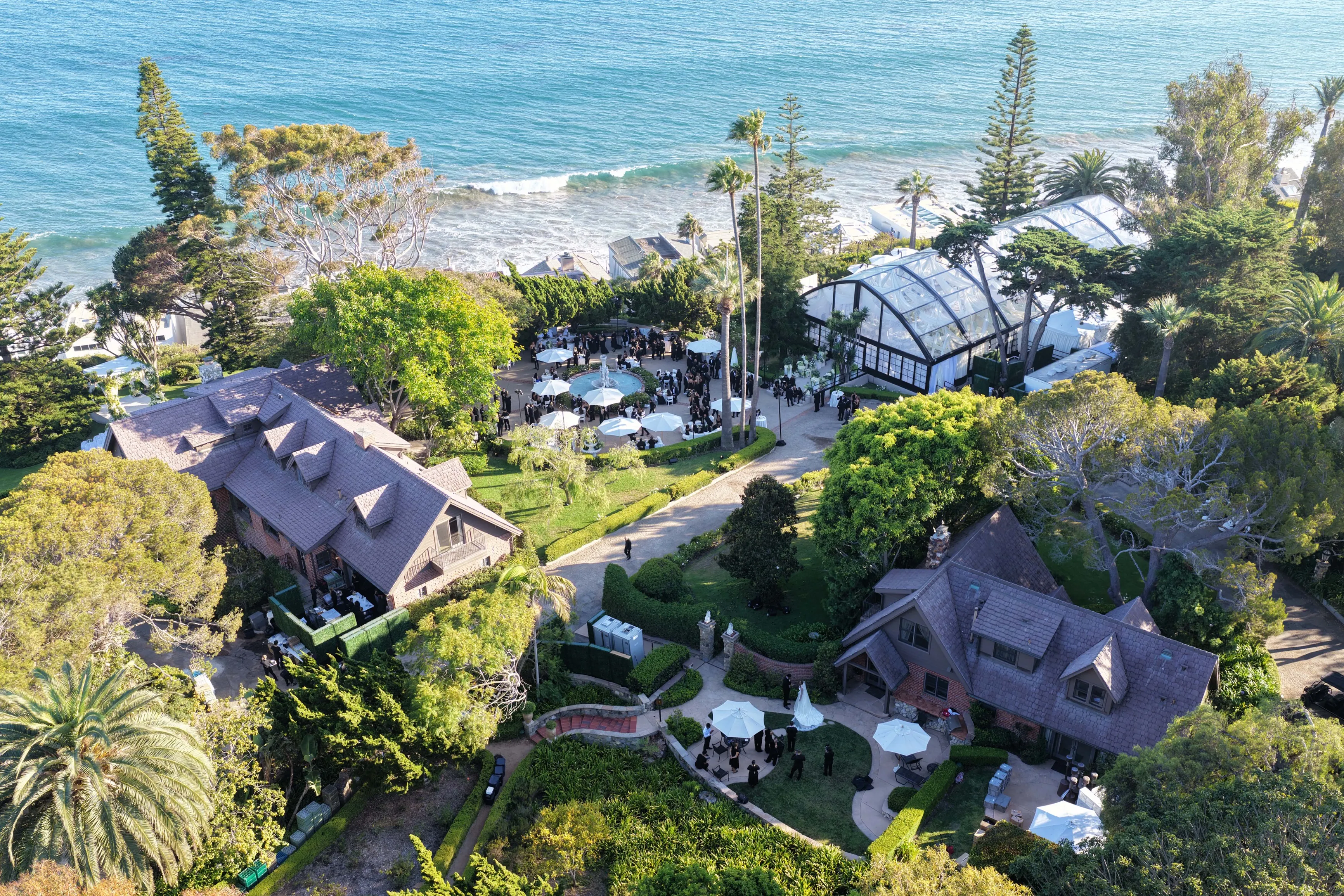An aerial view of Jordyn Woods and Karl-Anthony Towns' wedding ceremony in Malibu, California, with guests gathered in a garden overlooking the Pacific Ocean.