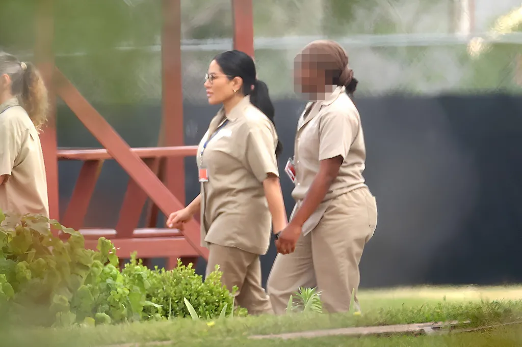 Jen Shah of The Real Housewives of Salt Lake City, wearing a beige prison uniform and glasses, walks with a fellow inmate.