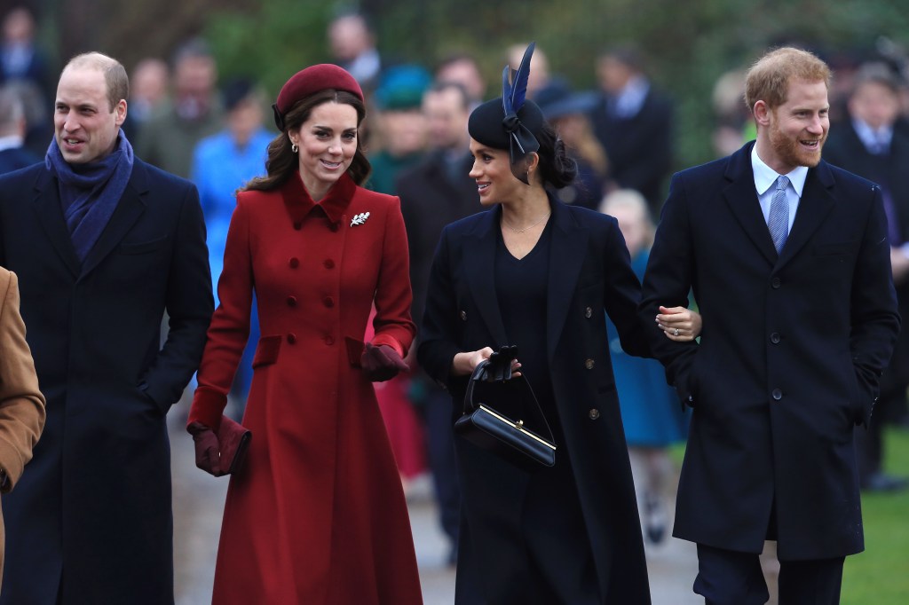 Prince William, in a blue coat and blue scarf, Kate Middleton in a red coat and red hat, Meghan Markle in a black coat and black dress and black hat, and Prince Harry, in a black coat, blue shirt and blue tie, walking together.