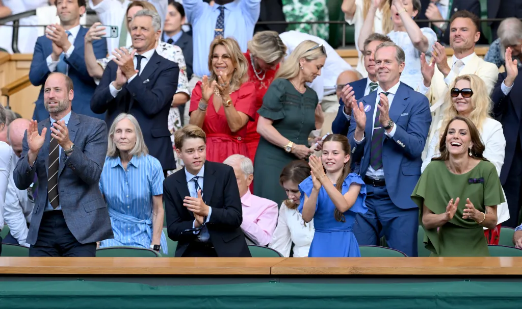 Prince William, in a blue blazer, blue shirt, brown striped tie and black pants, Prince George, in navy blue suit, Princess Charlotte, in a blue dress, and Catherine, Princess of Wales, in a green dress, clapping at Wimbledon.