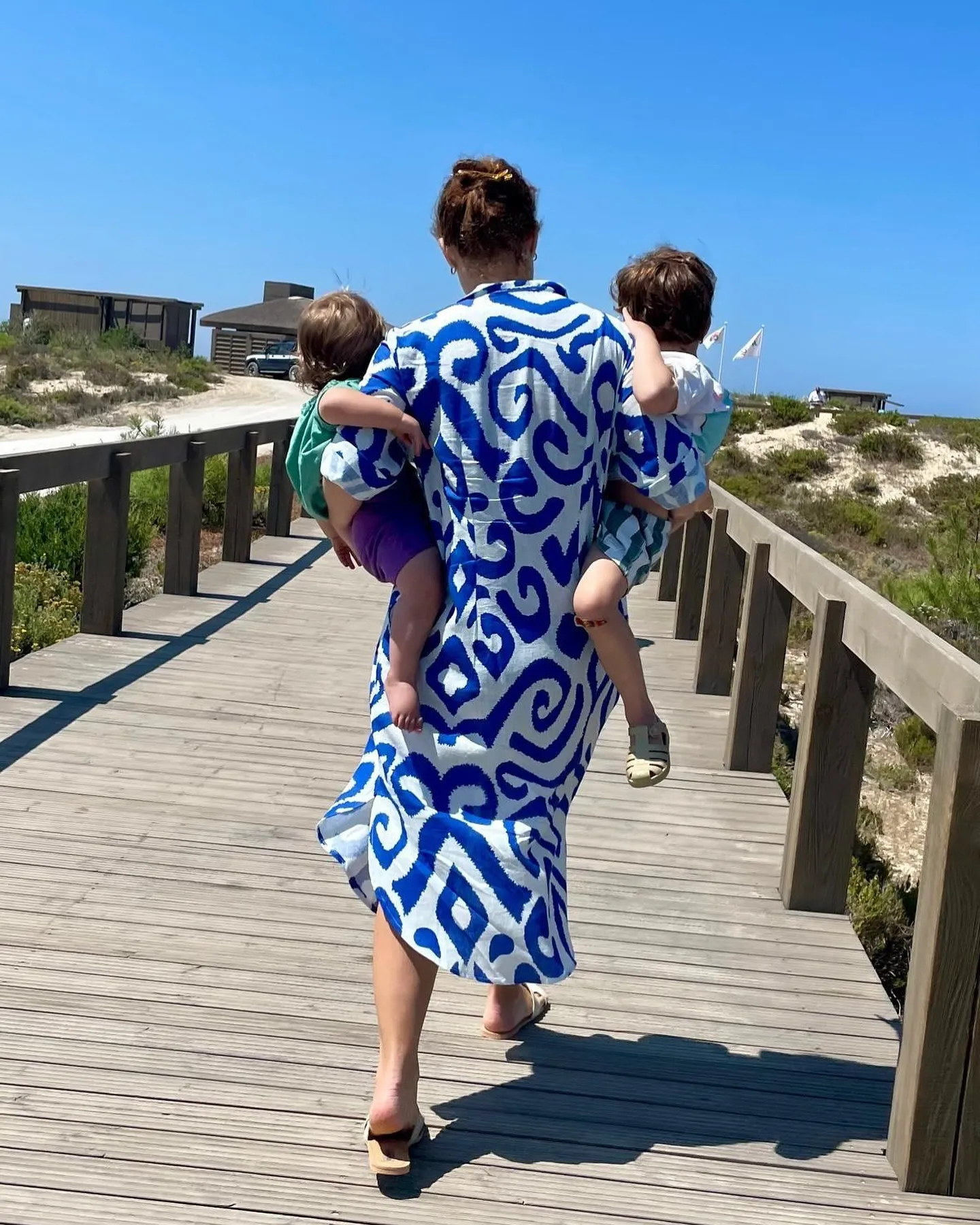 Princess Eugenie walking away on a boardwalk, carrying two children.