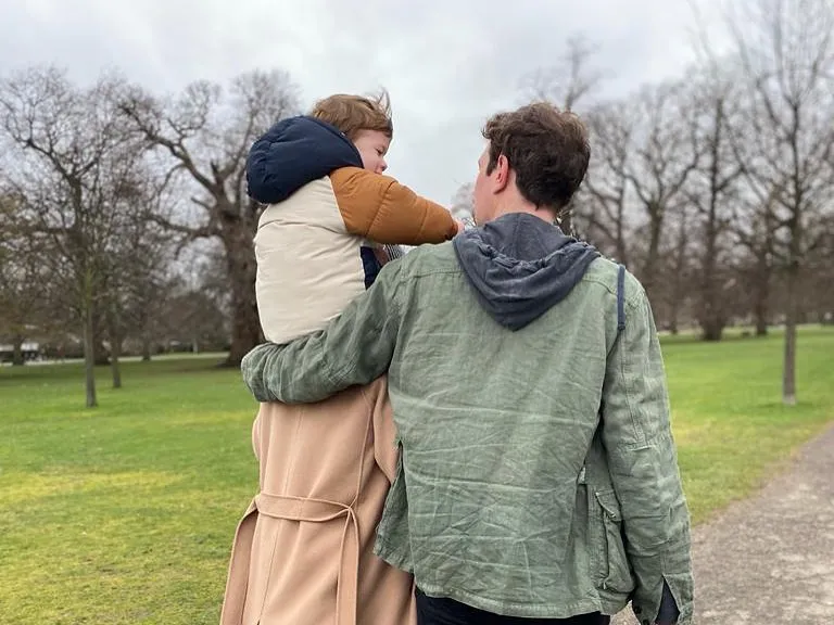 Princess Eugenie and Jack Brooksbank walking with their child, August, on Jack's shoulders.