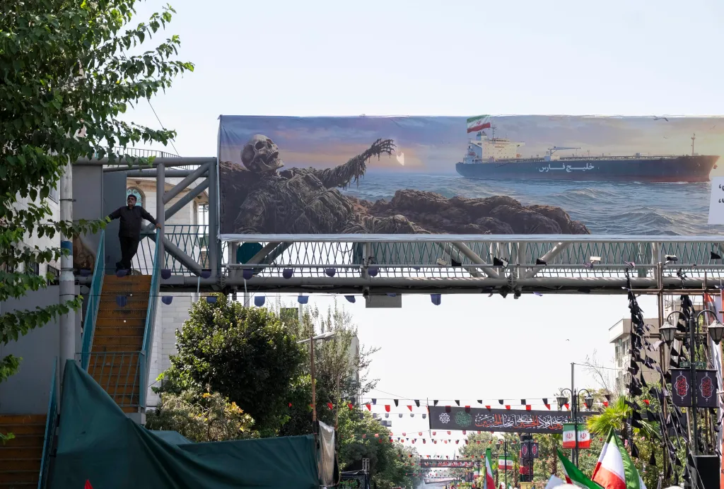 A pro-government mourner stands beside an anti-U.S. billboard on a bridge in Tehran, Iran.