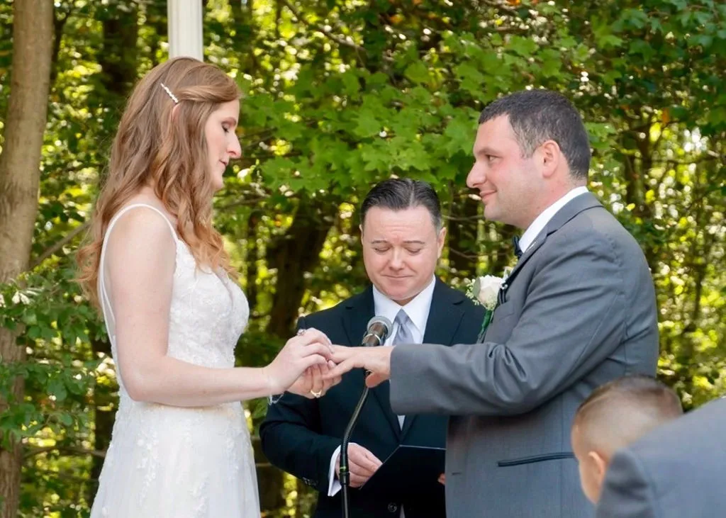 Rachel and Frank exchange rings during their wedding ceremony with an officiant looking on.