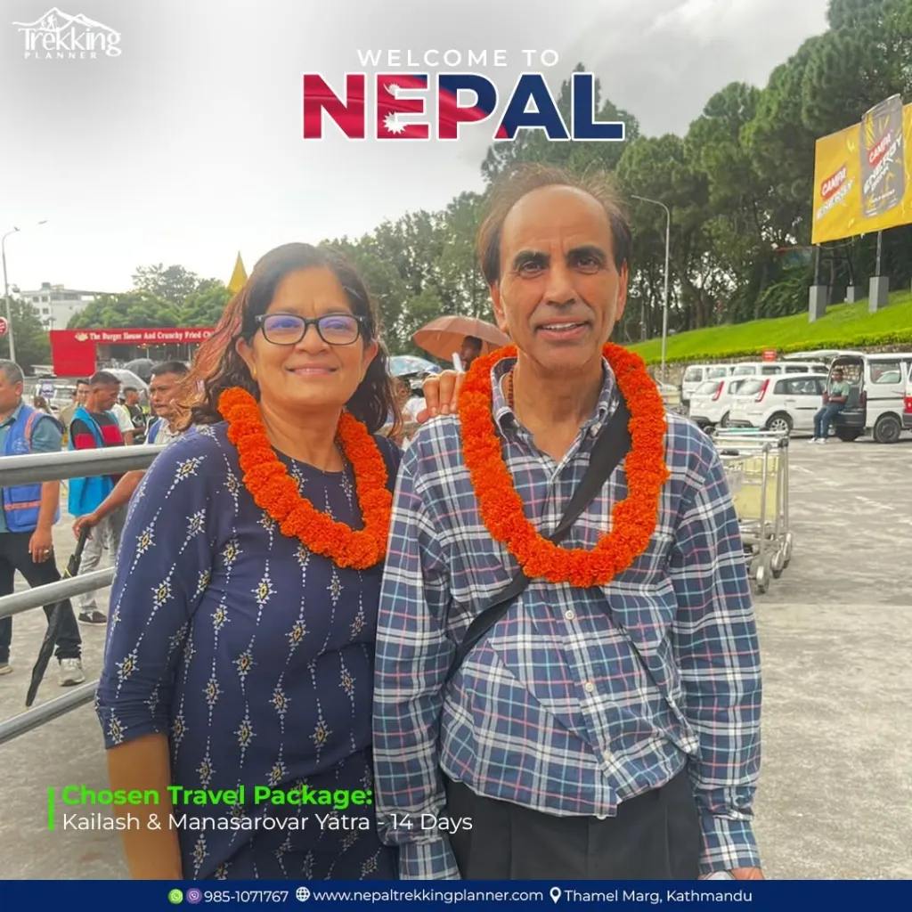 Ramesh and Neelam Sharma, wearing marigold garlands, standing outdoors with a 