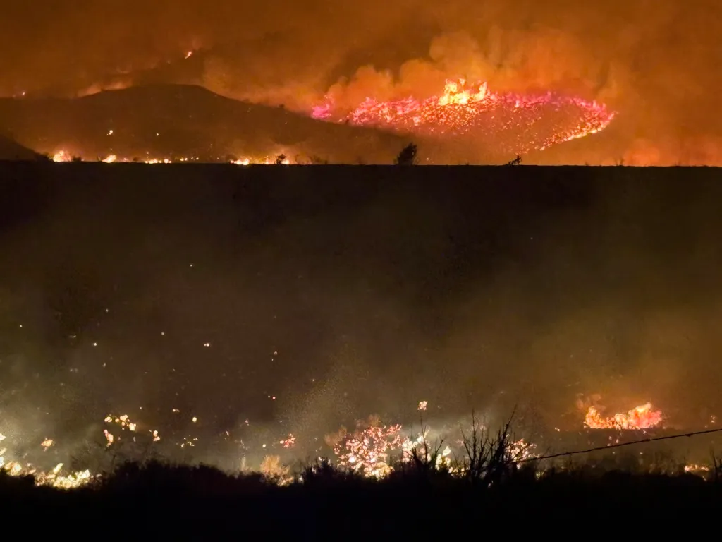 Wildfire burning across hillsides at night.