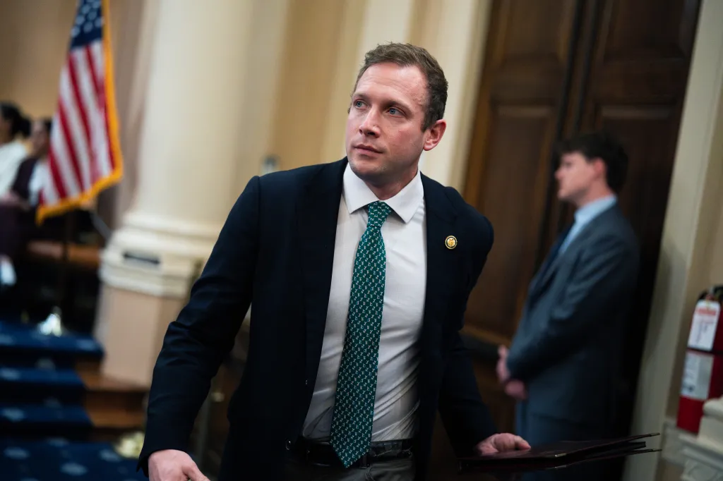 Rep. Max Miller in a suit and tie, holding a folder, attending the Ways and Means Committee hearing in the Longworth building.