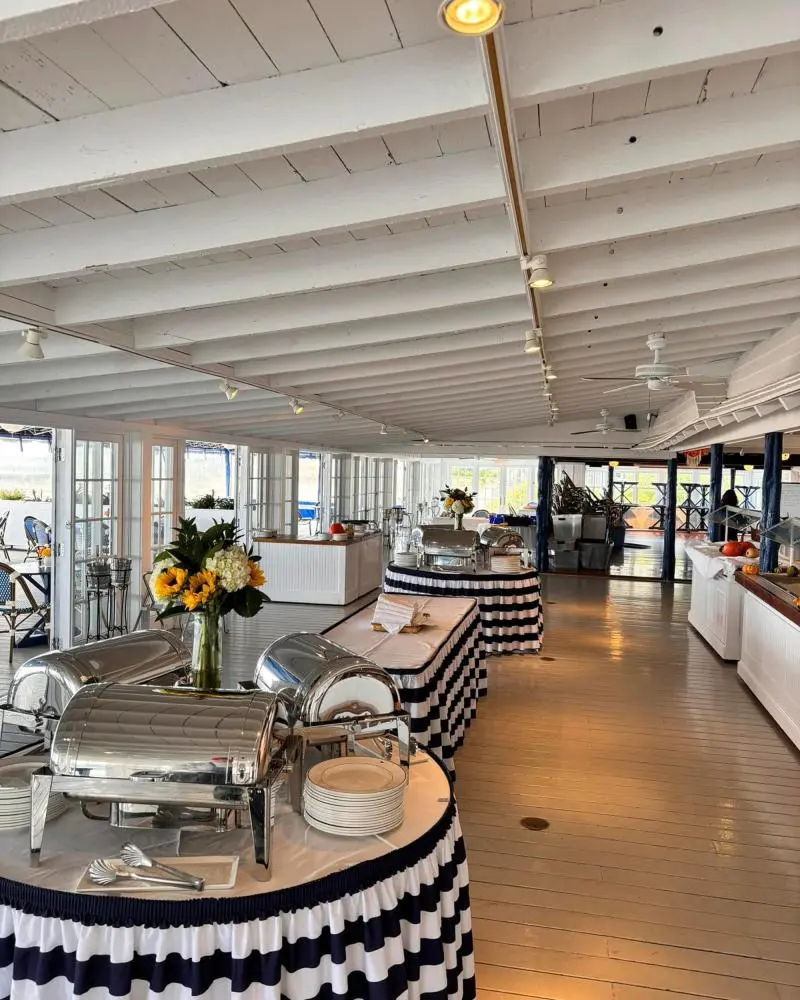 Interior of a Hamptons yacht club with buffet tables and white-washed wooden floors.