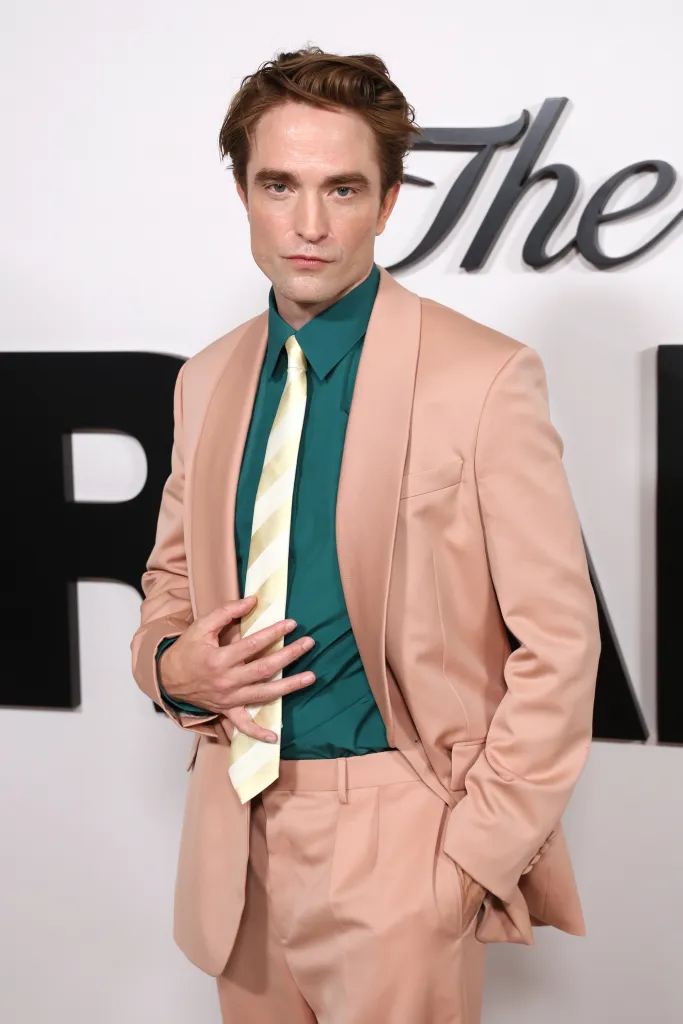 Robert Pattinson in a peach suit, green shirt, and striped tie.