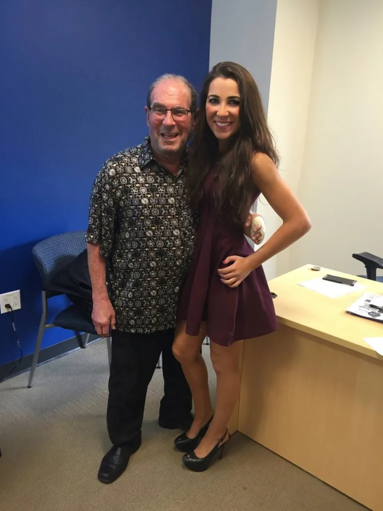 Ronn Owens and his daughter Laura Owens smiling while standing.