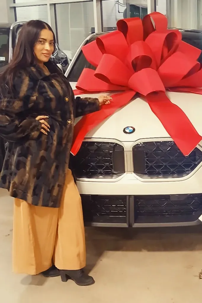 Rosana Kissoon, 39, stands next to a new white BMW with a large red bow on it.