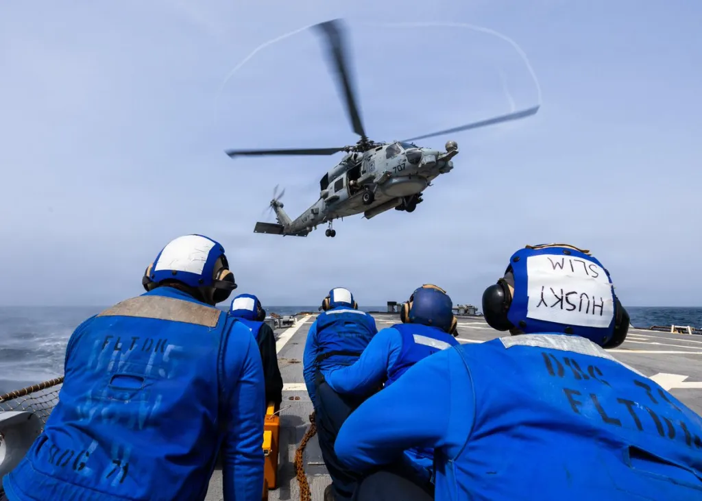U.S. Sailors observe an MH-60R Sea Hawk helicopter landing on the flight deck aboard USS Ross (DDG 71).