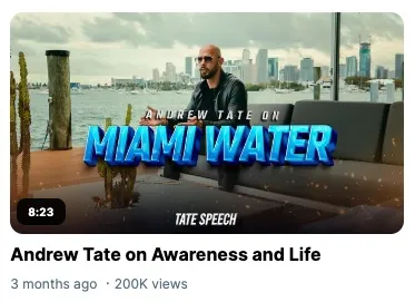 Andrew Tate sits on an outdoor sofa with a Miami skyline and water in the background, with
