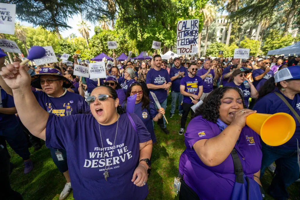 A crowd of state workers wearing purple SEIU Local 1000 shirts protest California Governor Gavin Newsom’s return-to-office policy.
