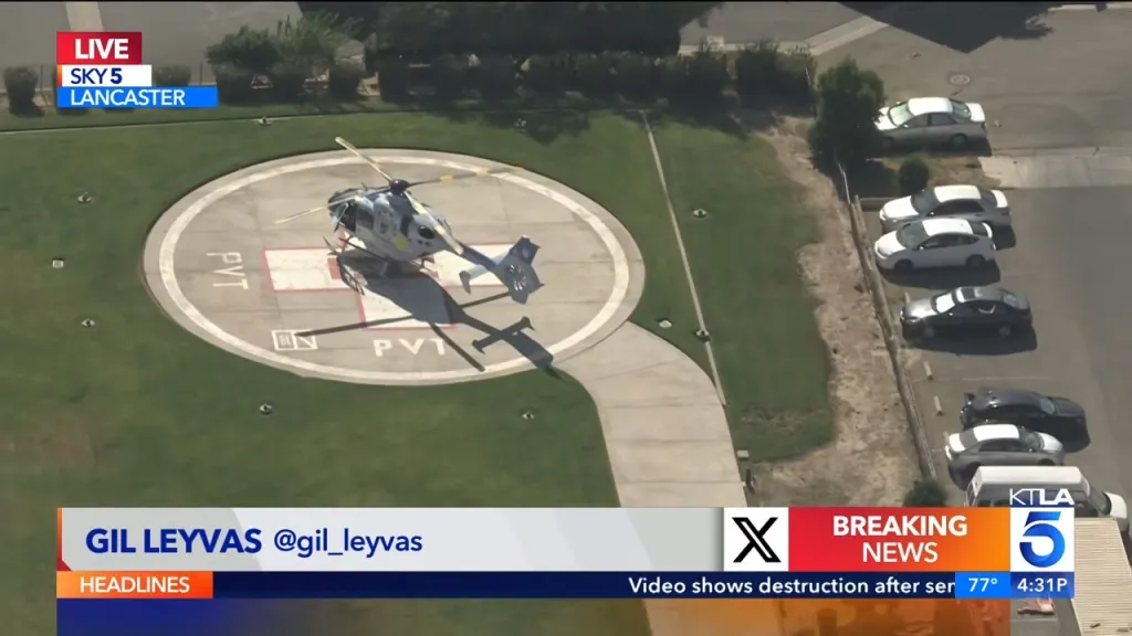 Overhead view of a helicopter on a helipad next to a parking lot.