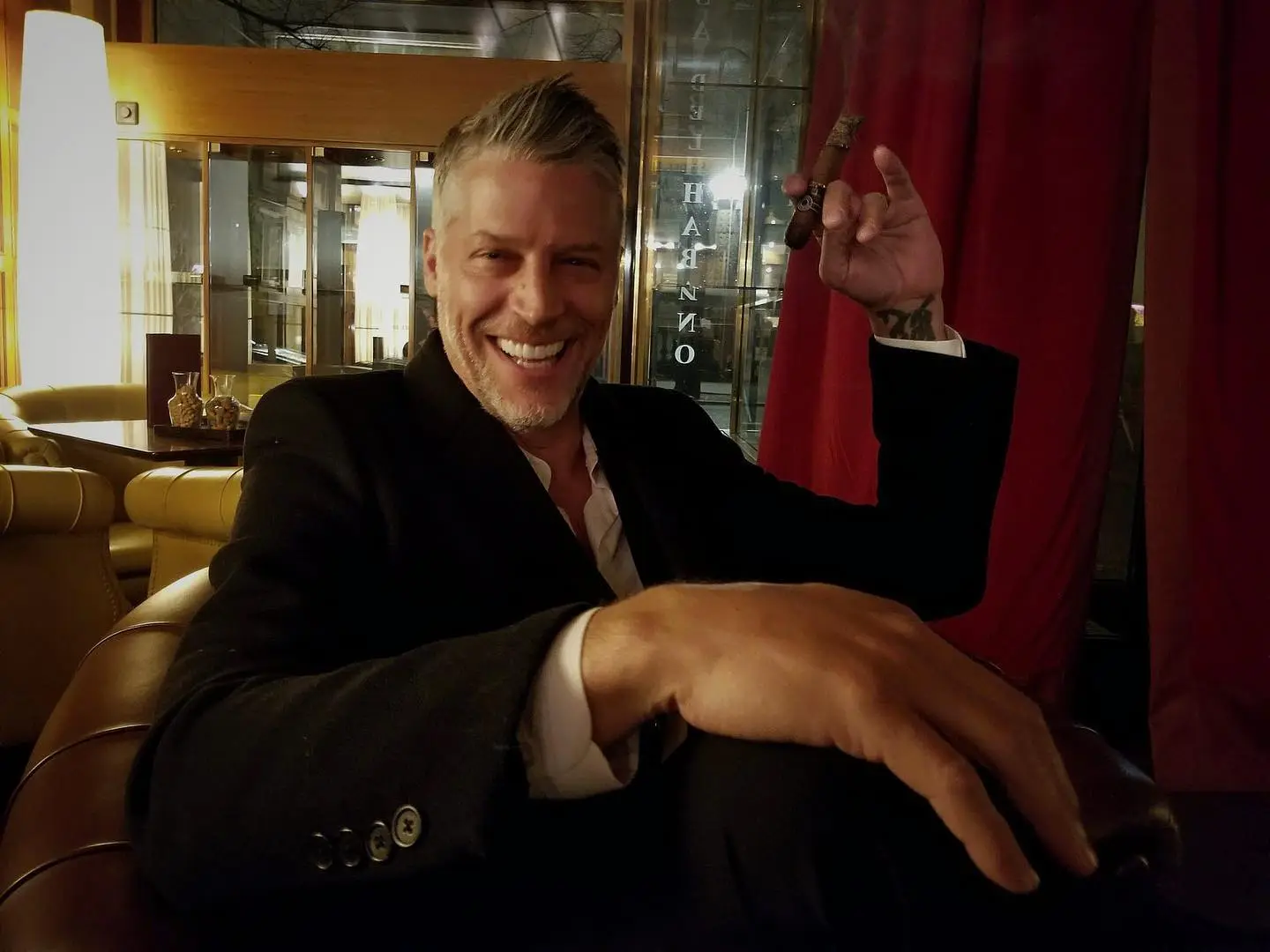 Bryan Randall sitting and smiling, holding a cigar.