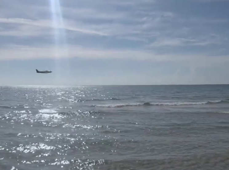 A small plane flying over the ocean before crashing.
