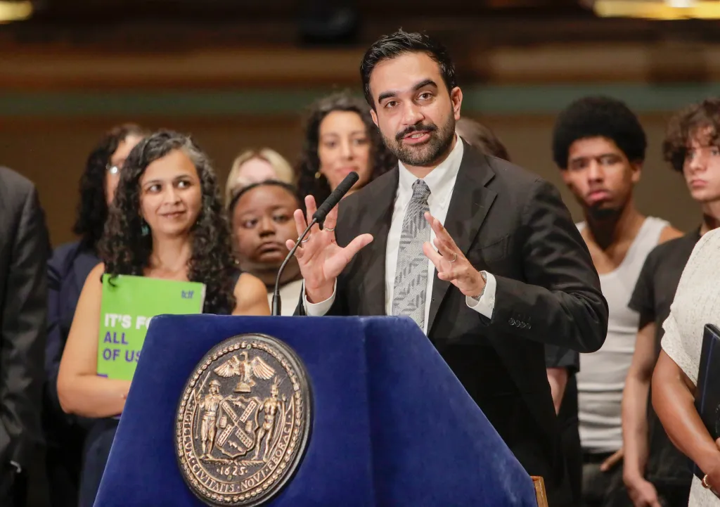 New York City Mayor Zohran Mamdani speaks at a press conference, gesturing with his hands.