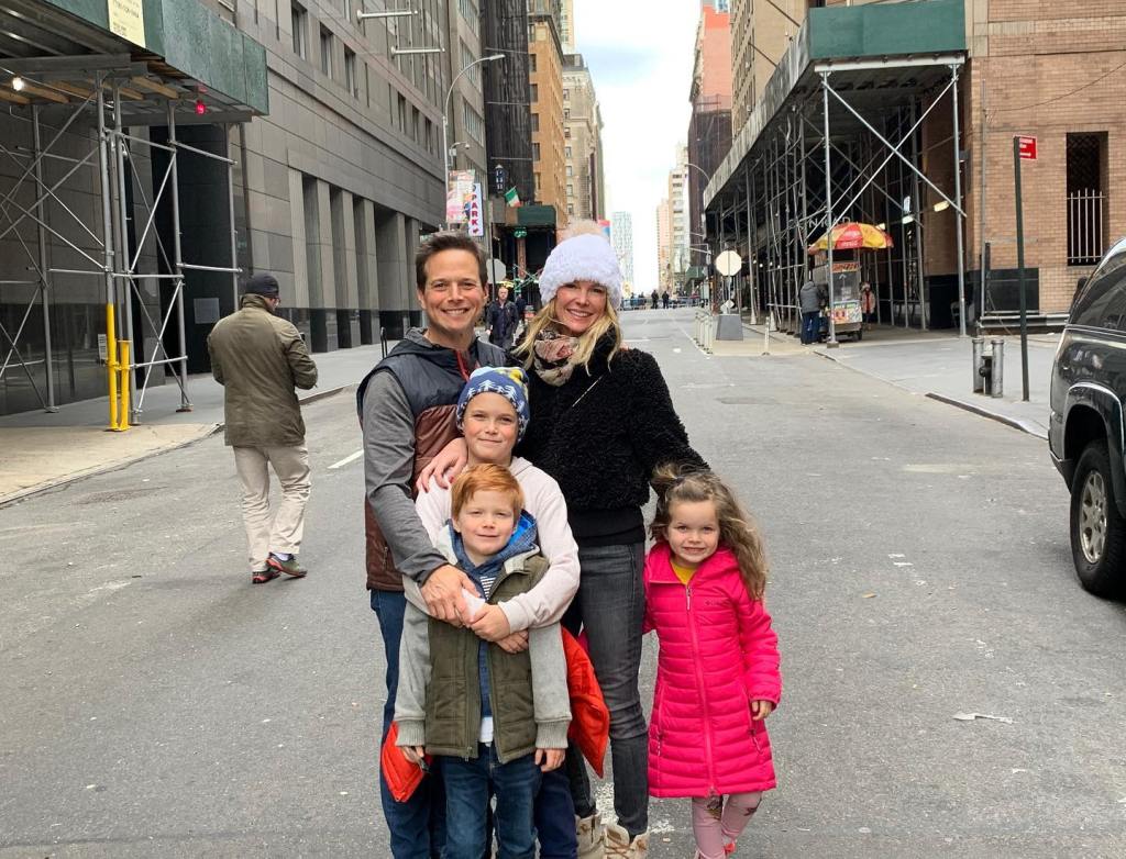 Scott Wolf, Kelley Wolf, and their three kids smiling at the camera in a city street.