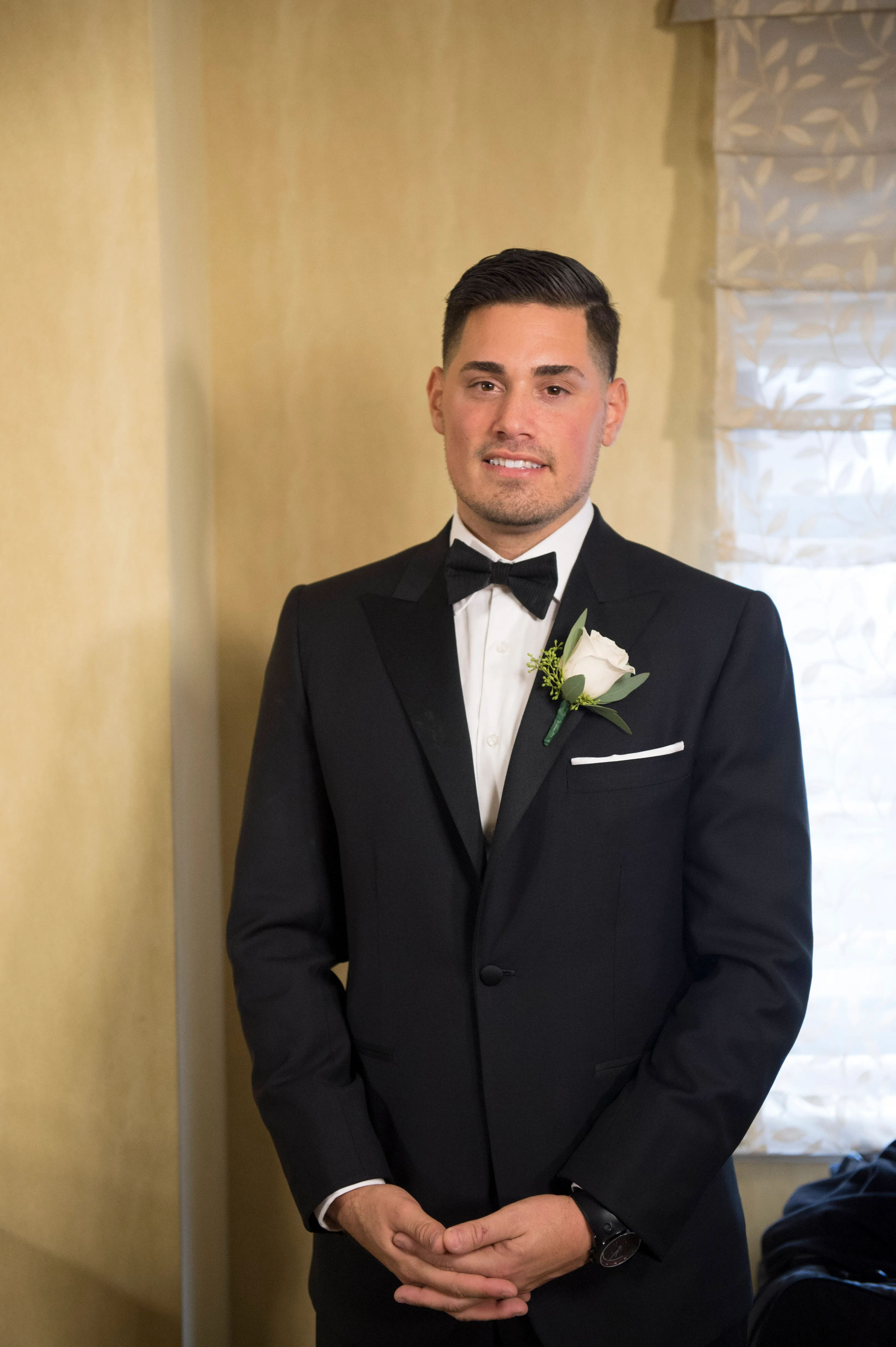 Ryan DeNino in a black tuxedo with a white rose boutonniere.