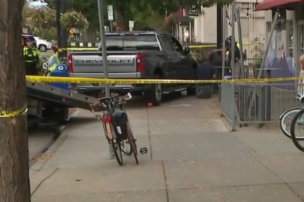 Police tape surrounds a pickup truck that drove onto a sidewalk, striking pedestrians.