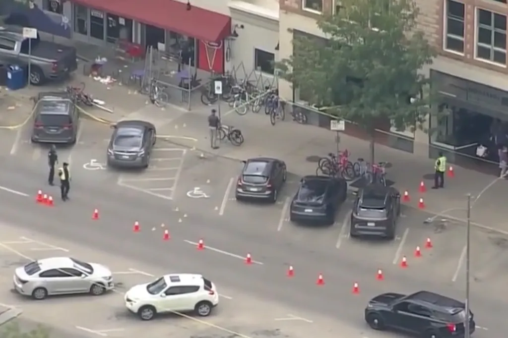 Overhead view of a street and sidewalk cordoned off by police tape and traffic cones, with police officers investigating after a driver struck pedestrians.